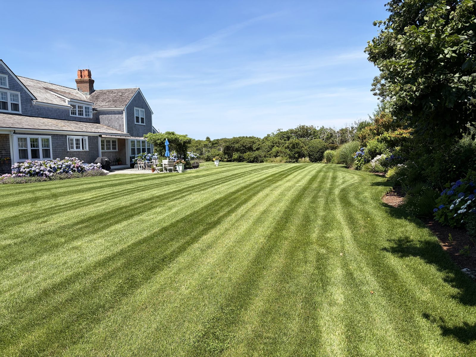 Freshly striped lawn sweeping up to a shingled Nantucket estate maintained by Ryan Conway Landscaping